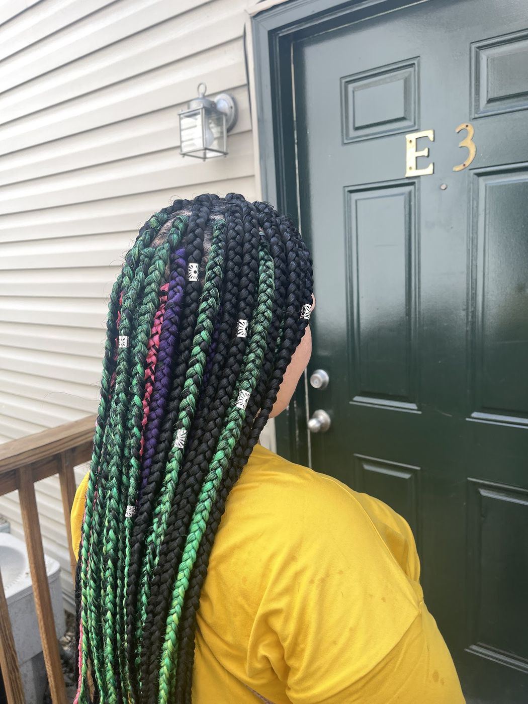 Long braids in green and purple with gold cuffs